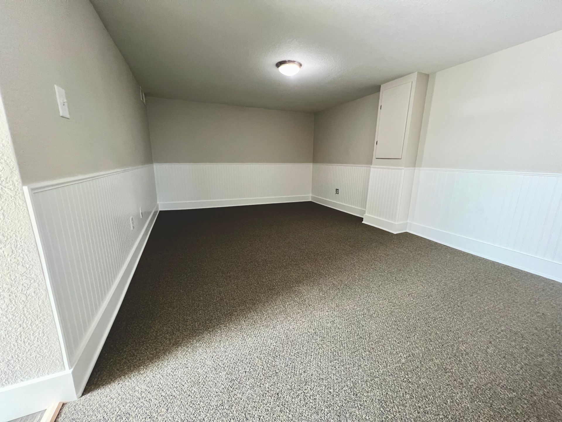 An empty room with a carpeted floor and white walls.