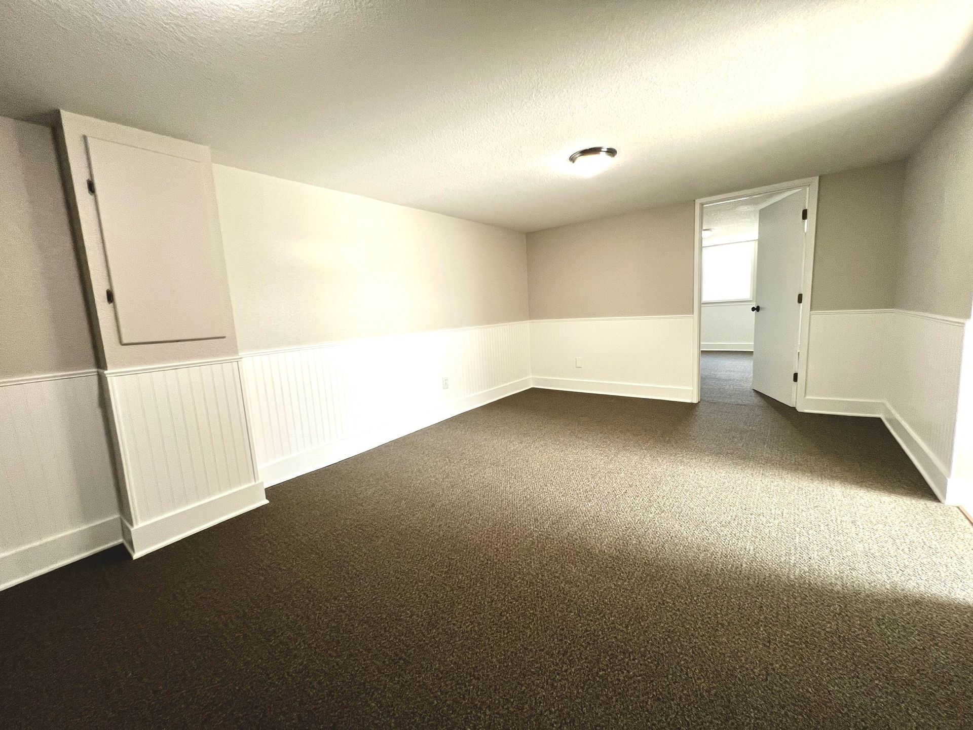 An empty room with a carpeted floor and white walls.