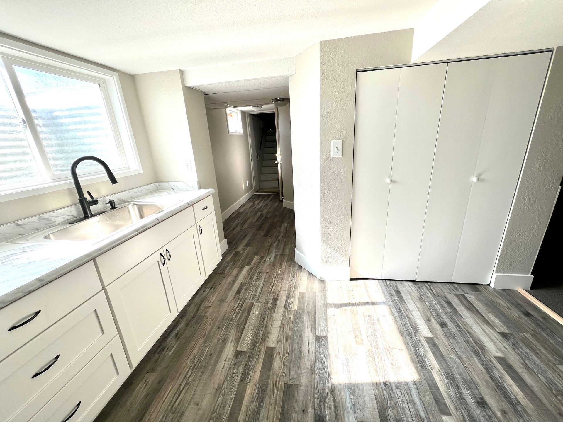A kitchen with a sink , cabinets , drawers and a window.