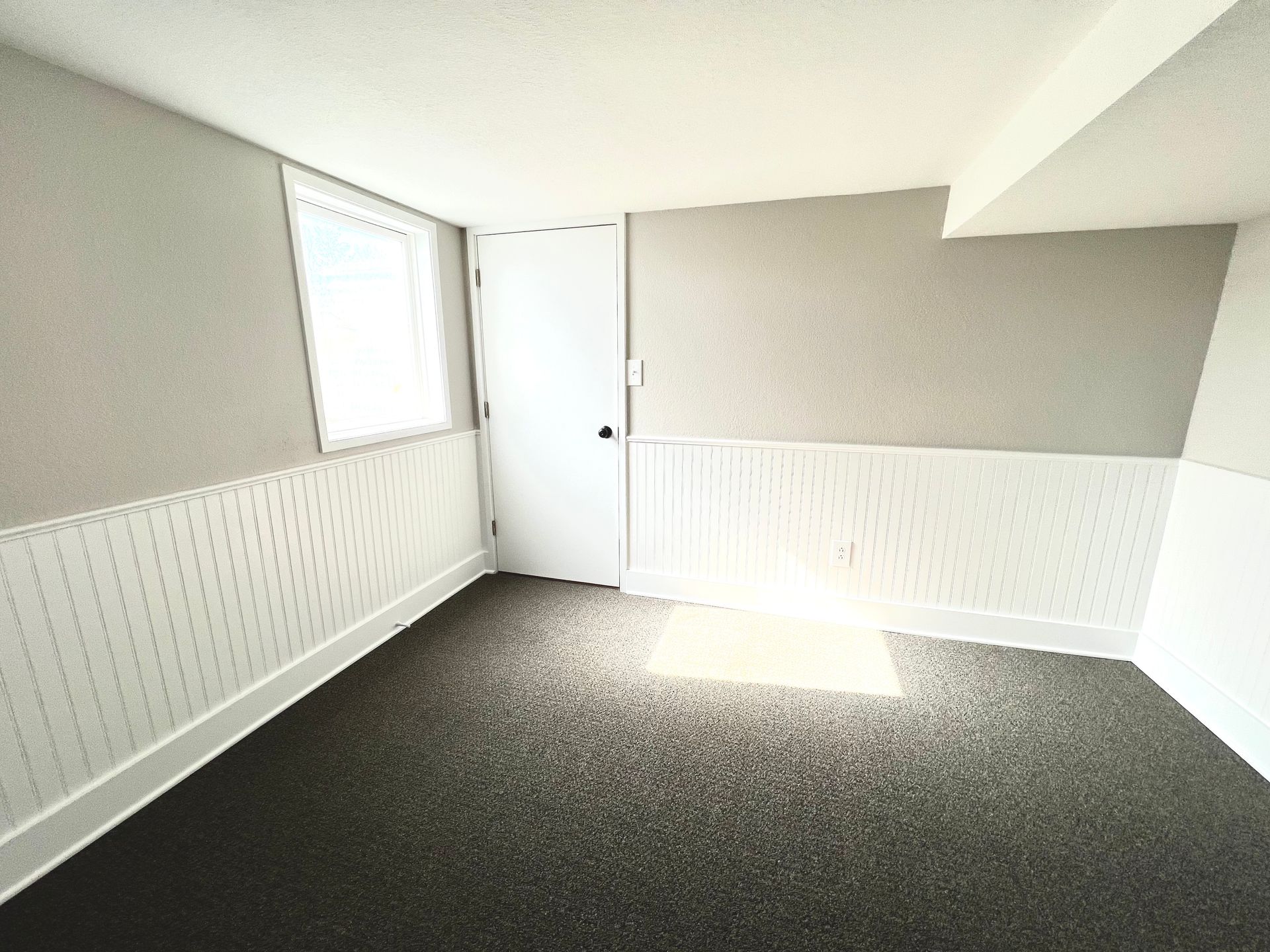 An empty room with a window and a door.