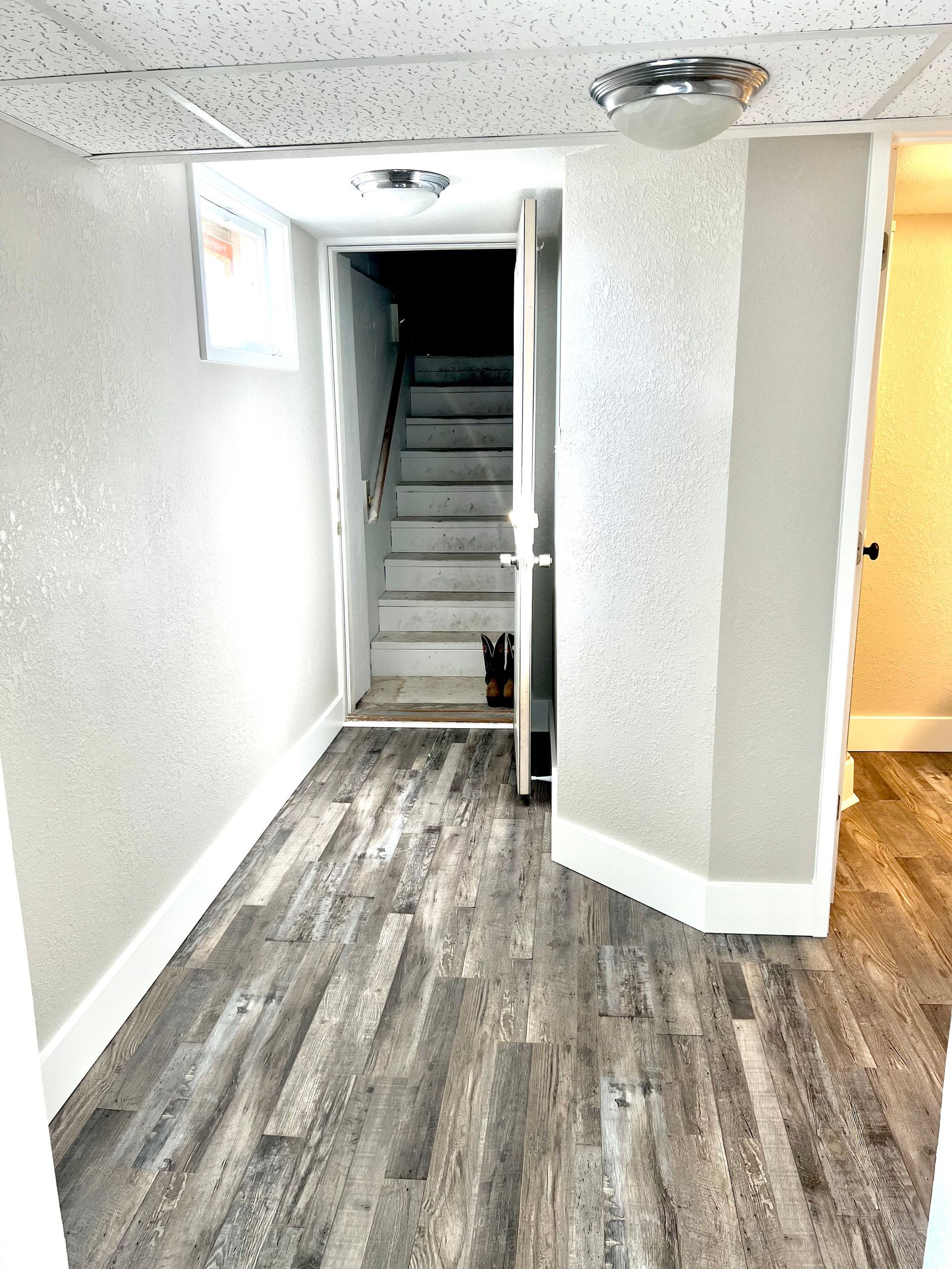 A hallway with wooden floors and stairs leading to the basement