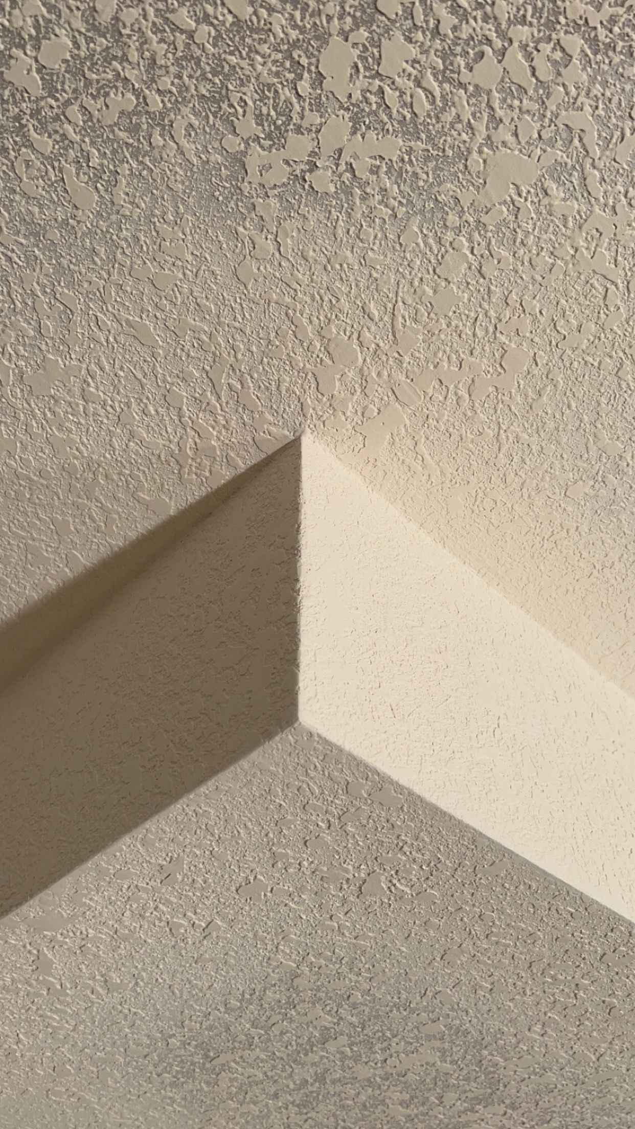A close up of a corner of a wall with a shadow on it.