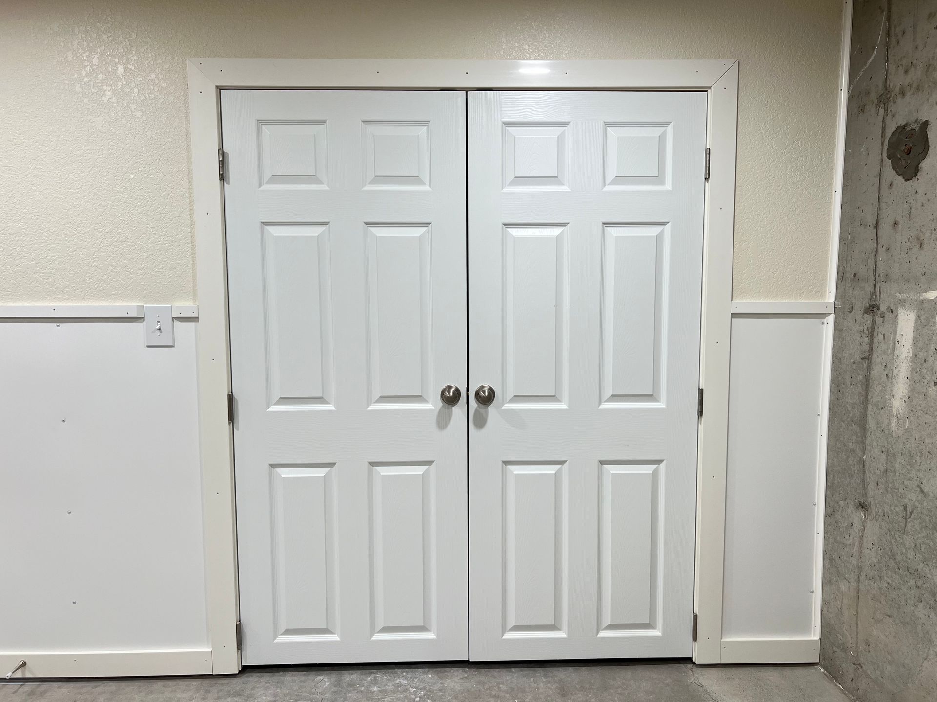 A pair of white doors are sitting next to each other in a room.
