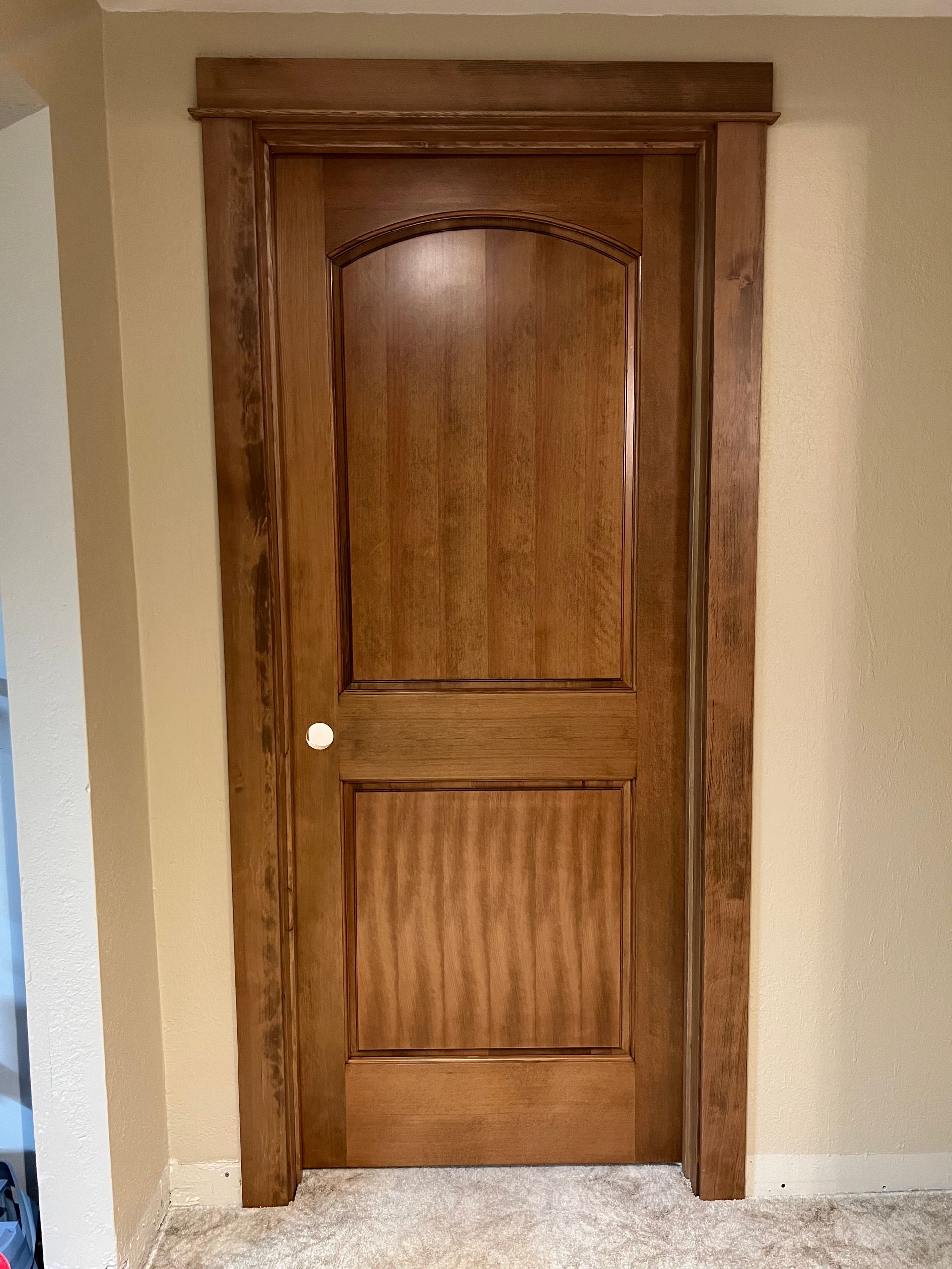 A wooden door is sitting in a hallway next to a wall.