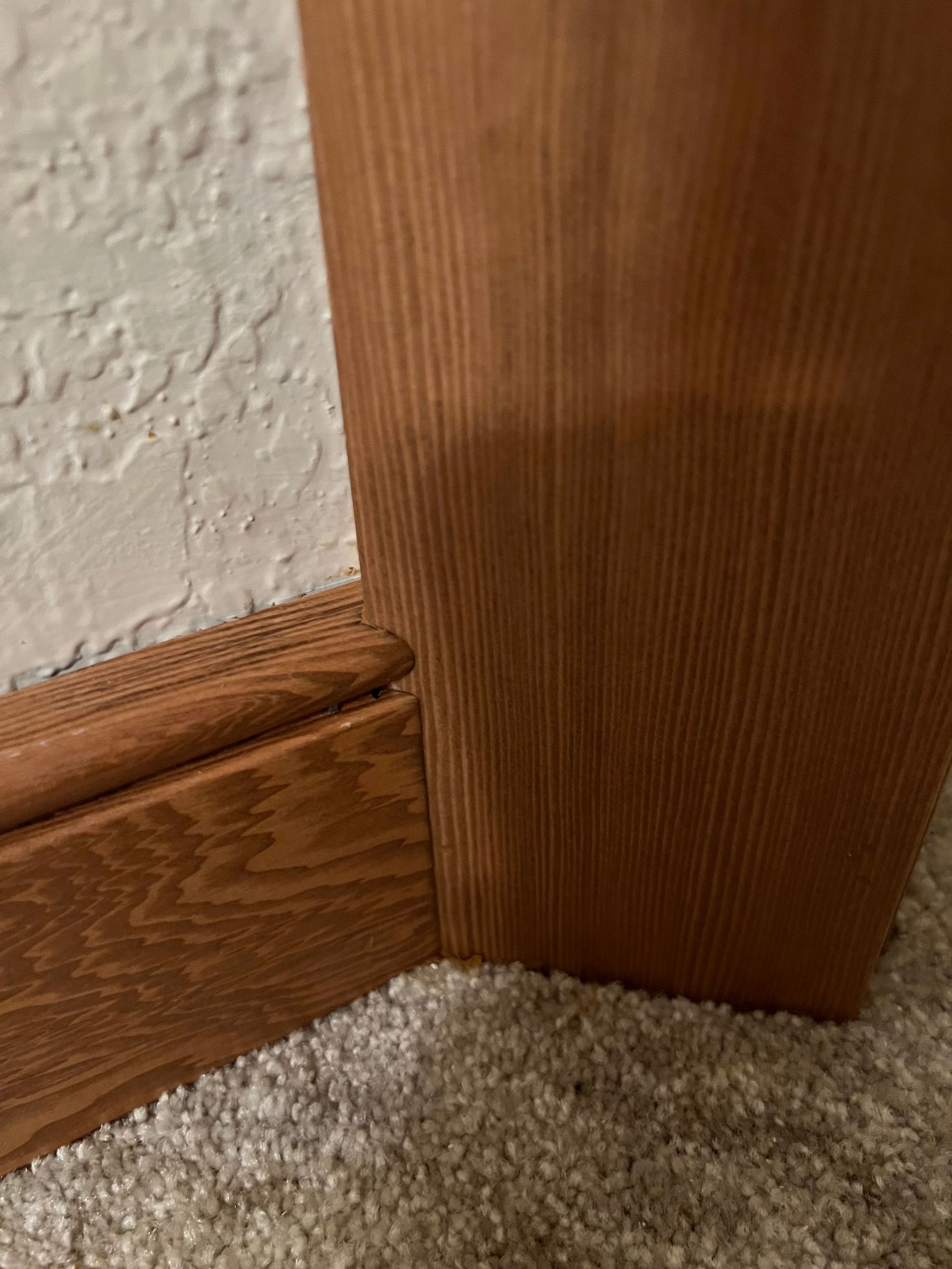 A close up of a wooden door molding on a carpeted floor.