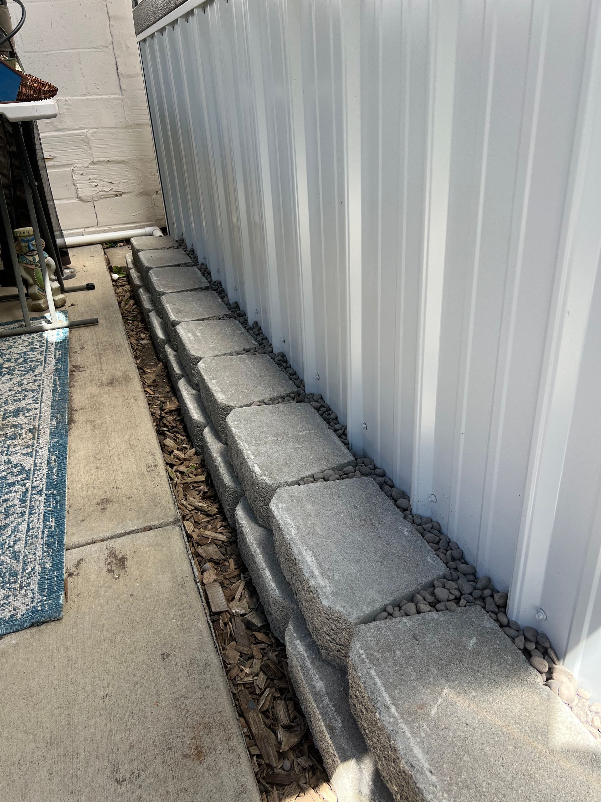 A white fence is sitting next to a brick wall.