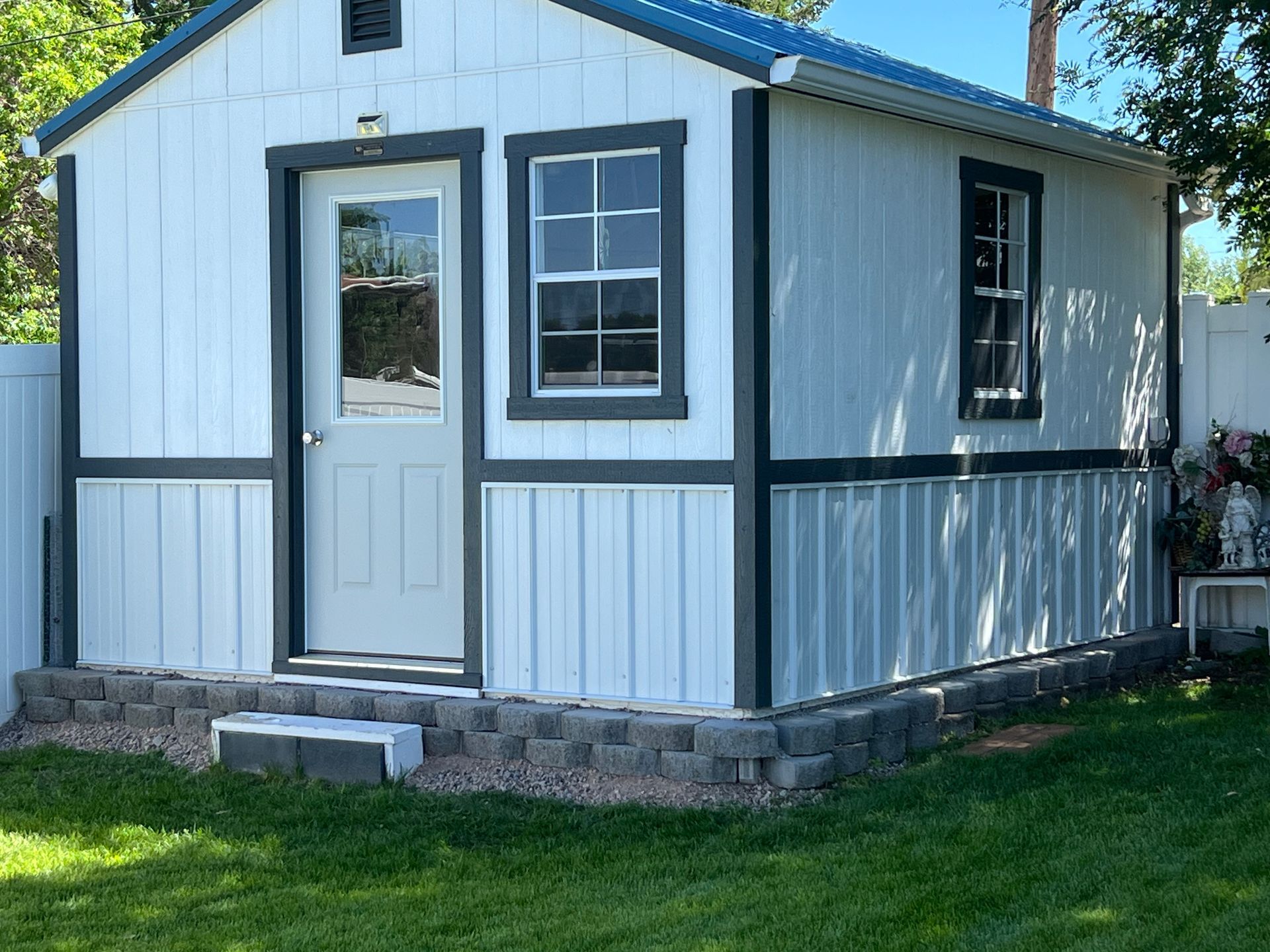 A white shed with a blue roof and black trim