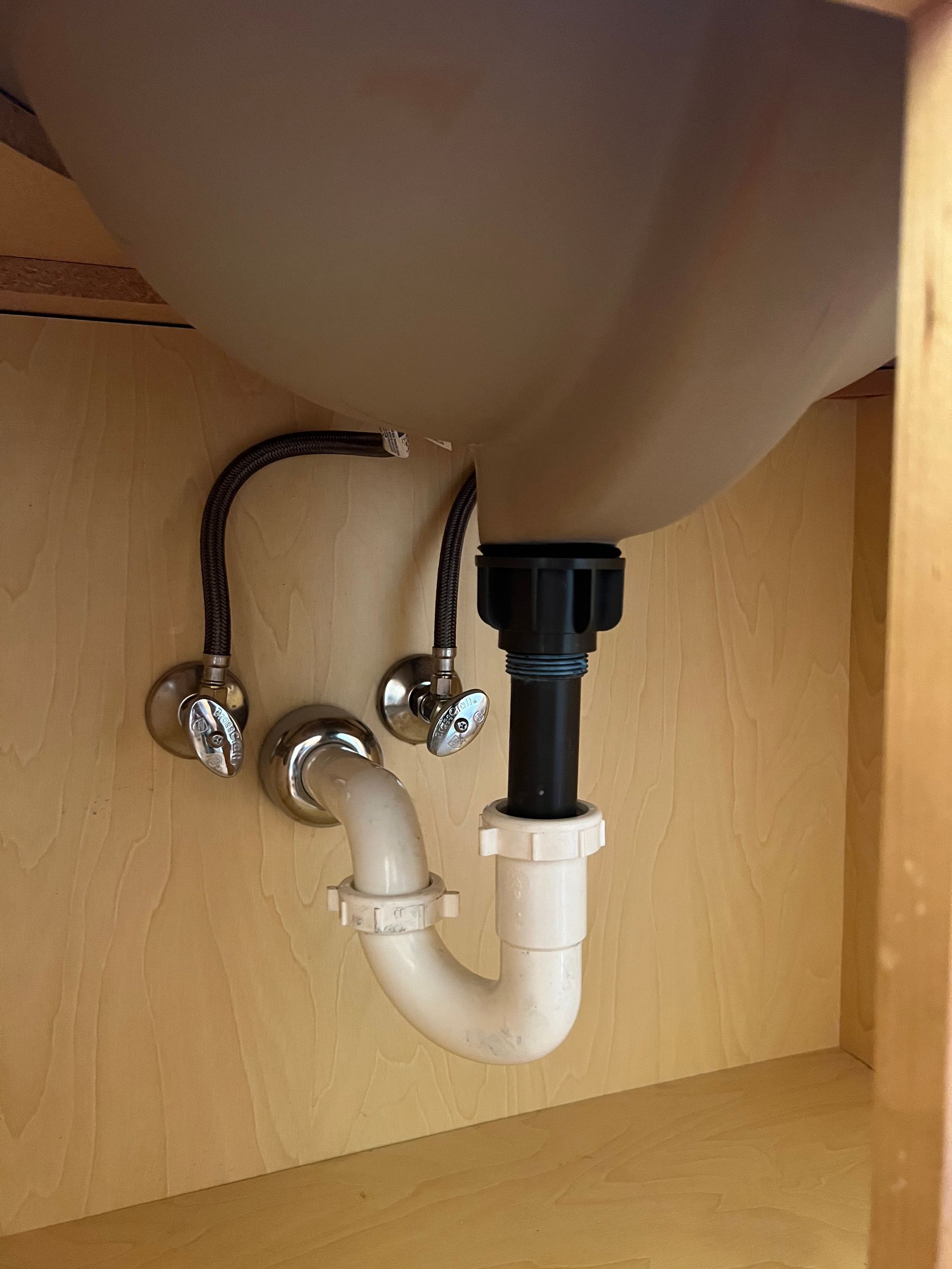 A sink with a plumbing pipe underneath it in a cabinet.