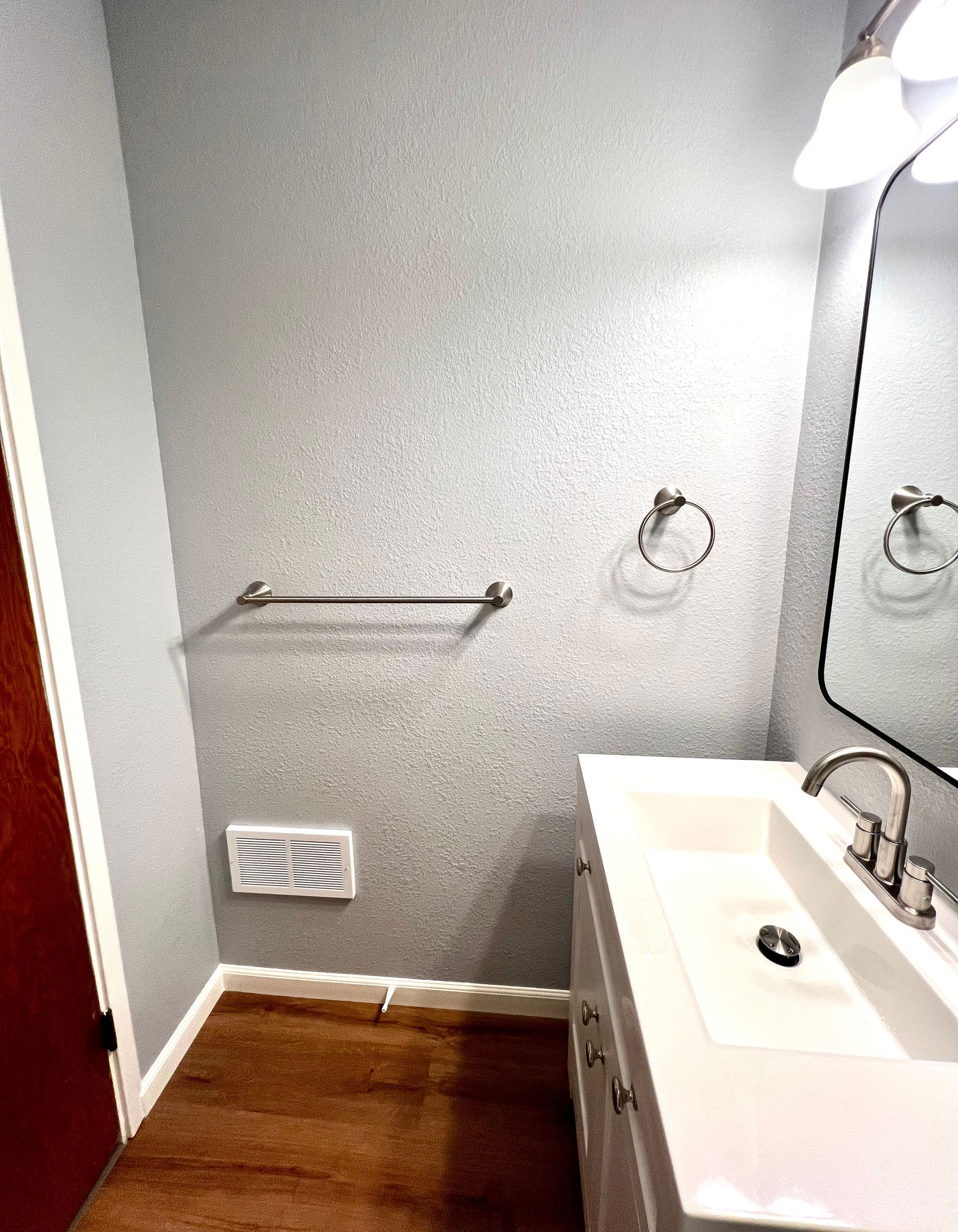 A bathroom with a sink , mirror and towel rack