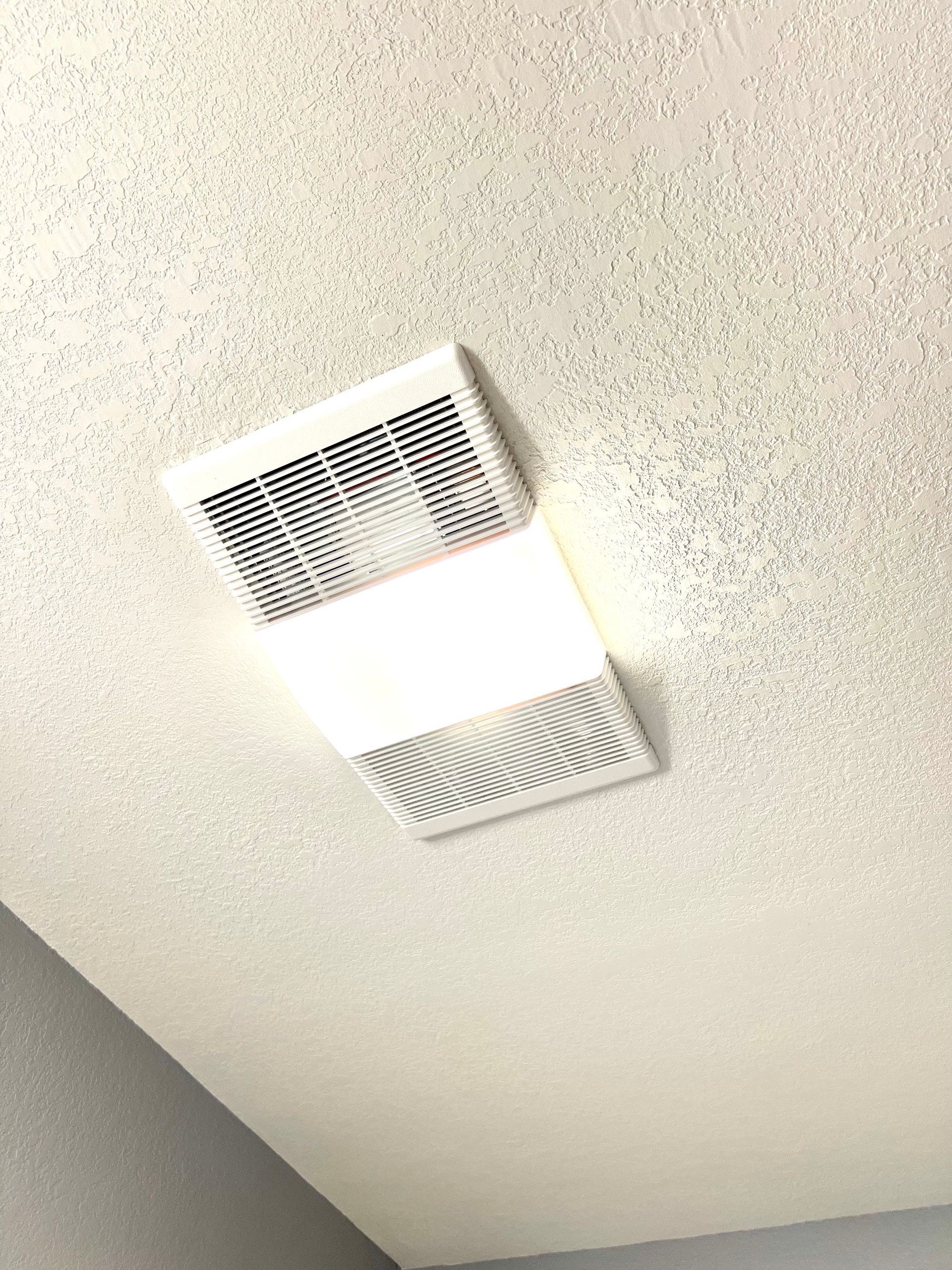 A white vent is hanging from the ceiling of a room.