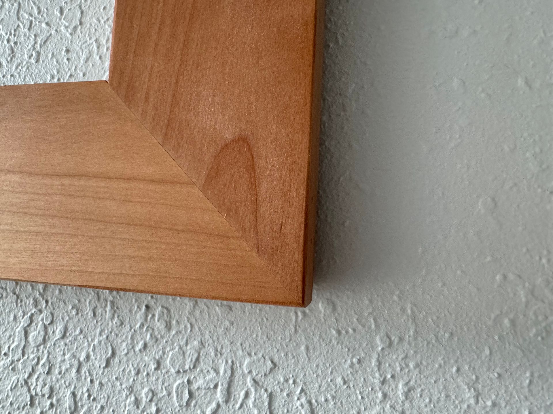 A wooden frame is hanging on a white wall.