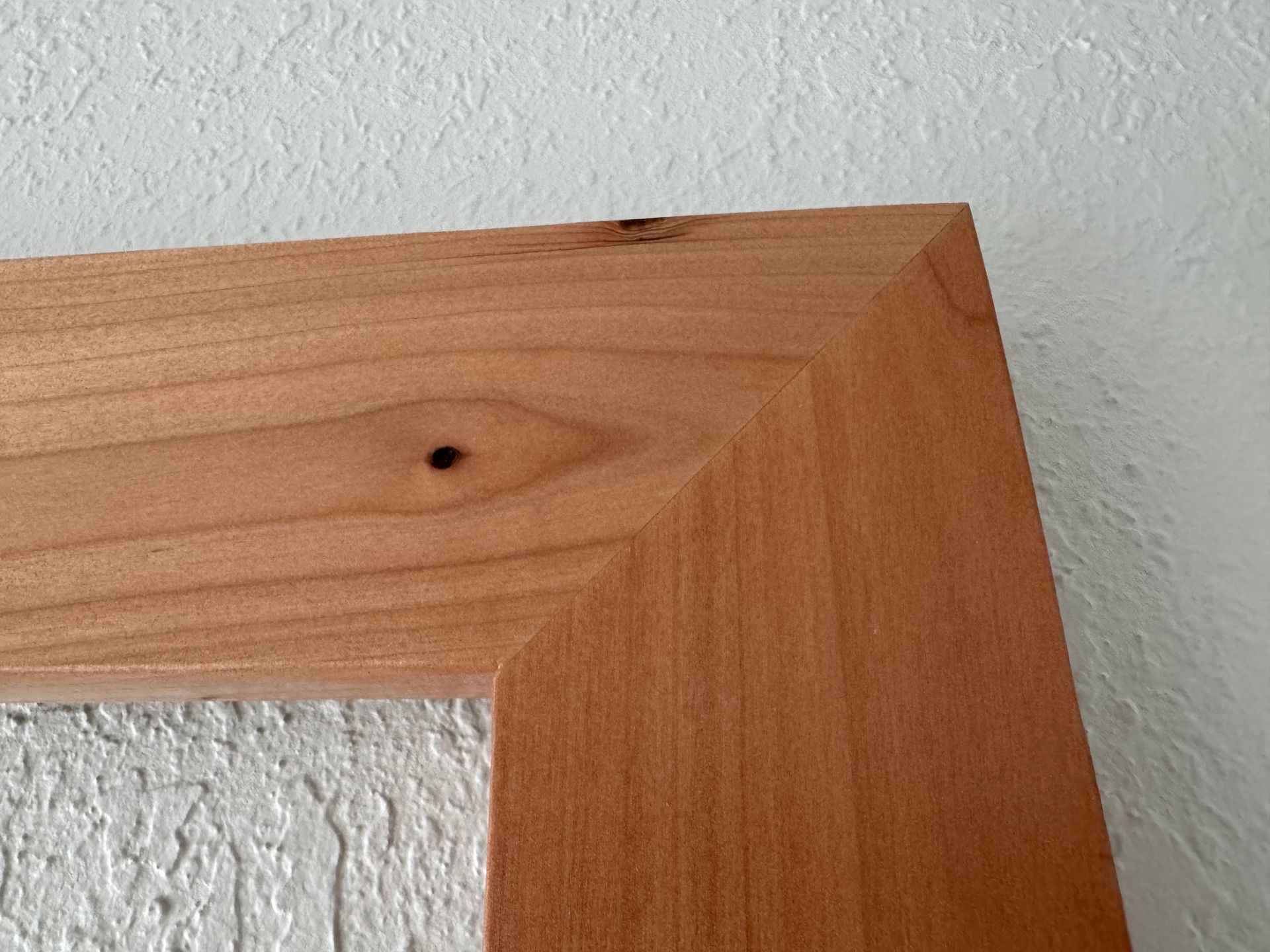 A close up of a wooden frame on a white wall.