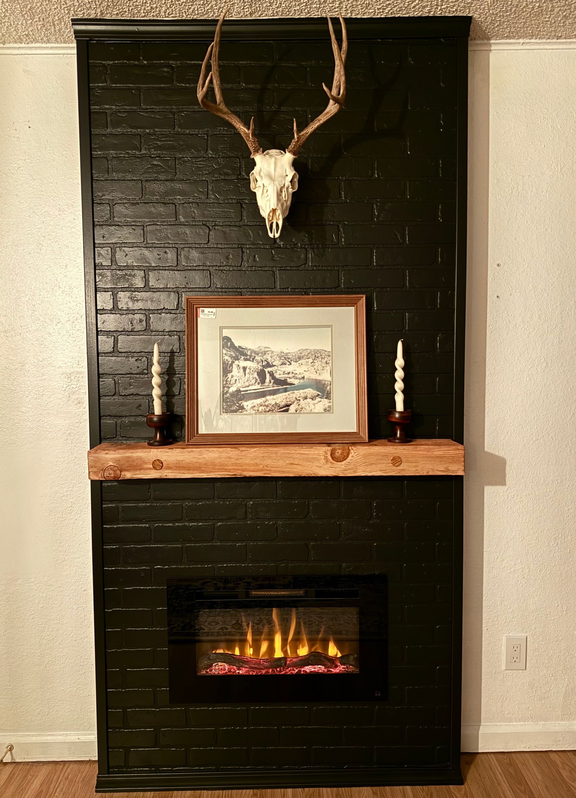 A black brick fireplace with a deer skull hanging above it.