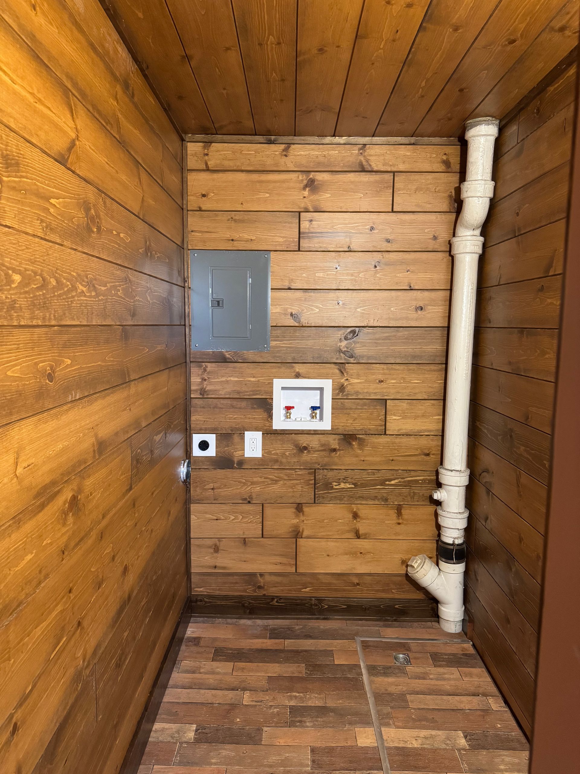 A bathroom with wooden walls and a white pipe