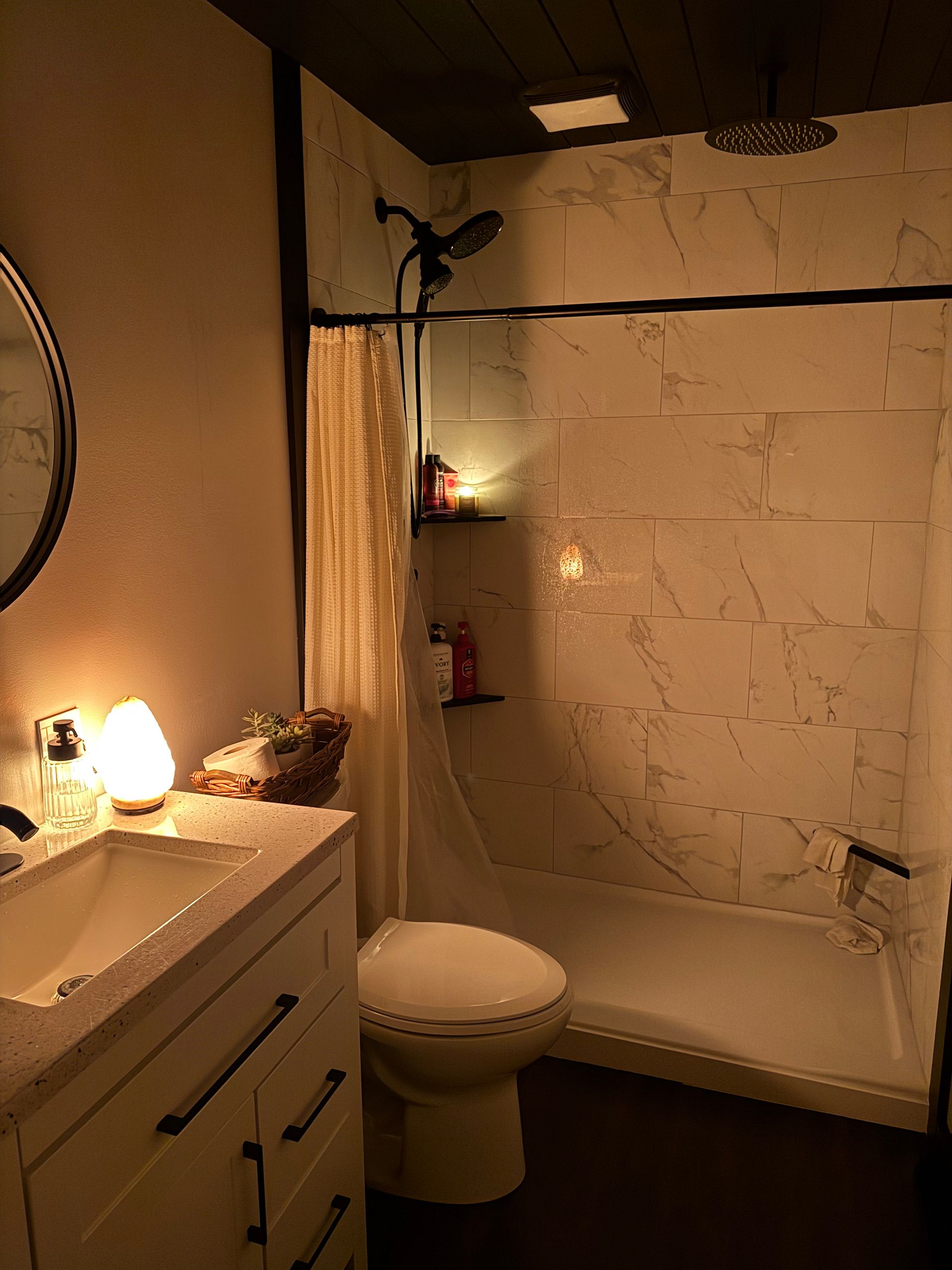 A bathroom with a toilet , sink , shower and mirror.