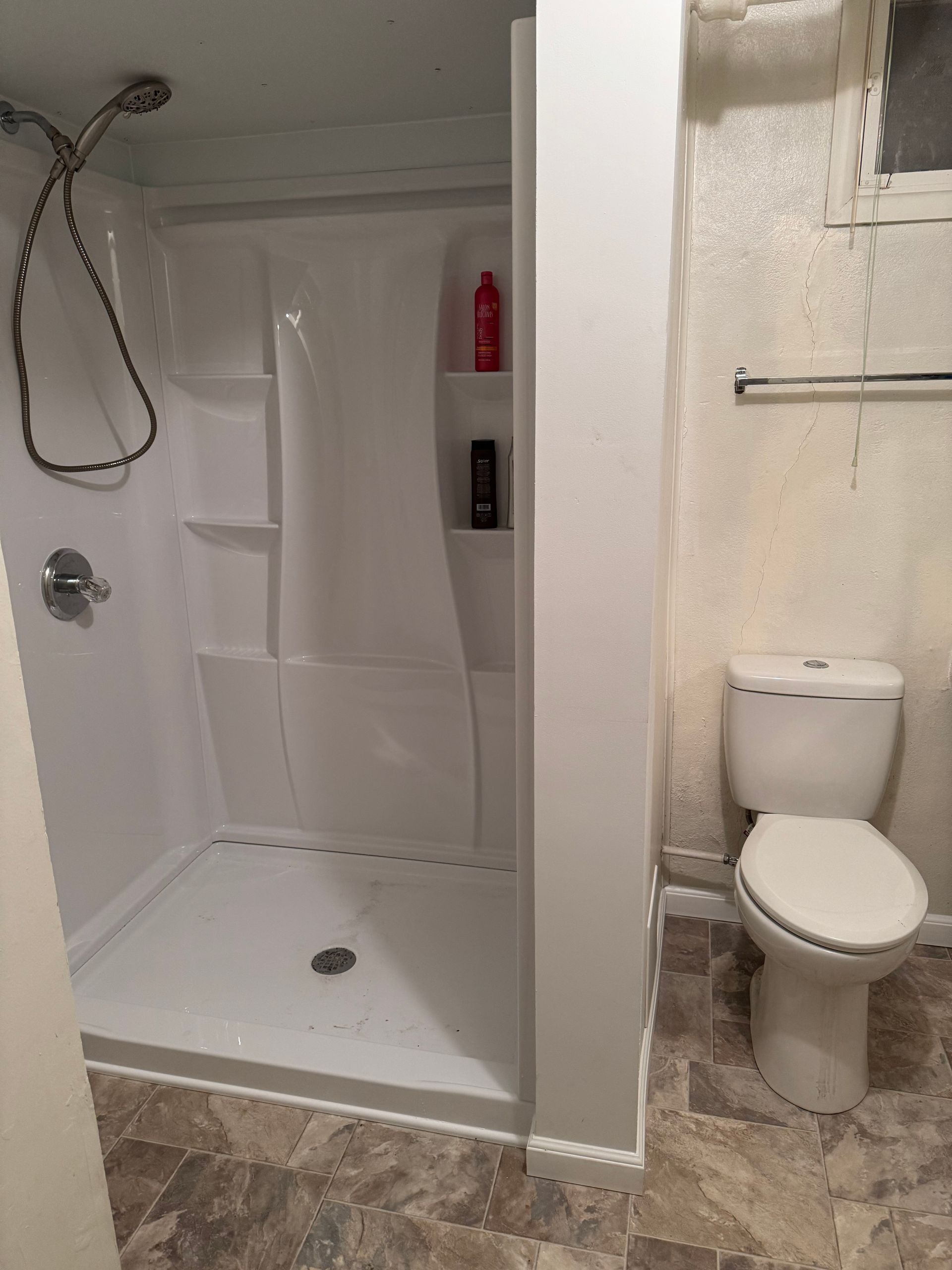 A bathroom with a toilet and a shower stall.