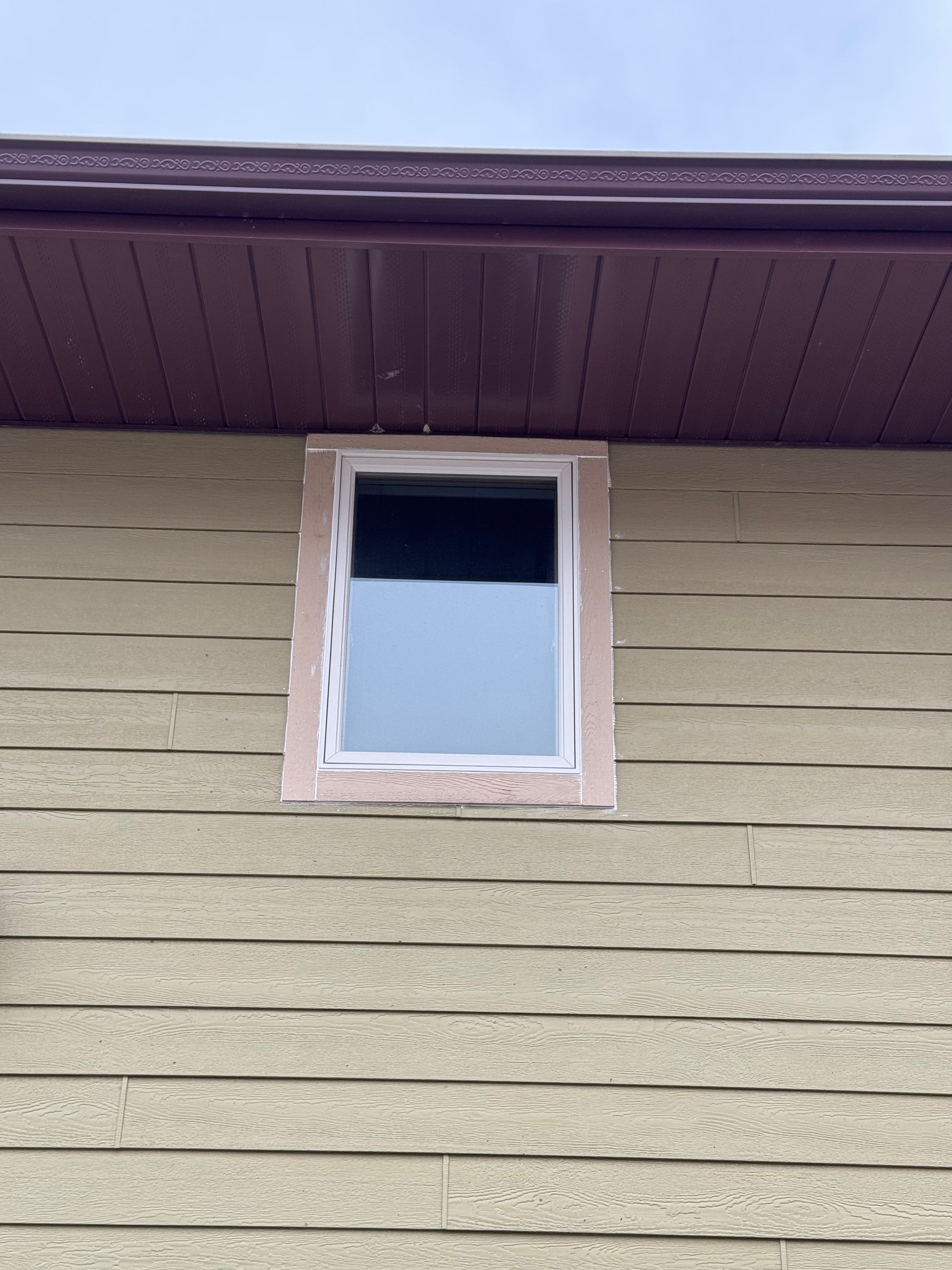 A window on the side of a house with a purple roof.
