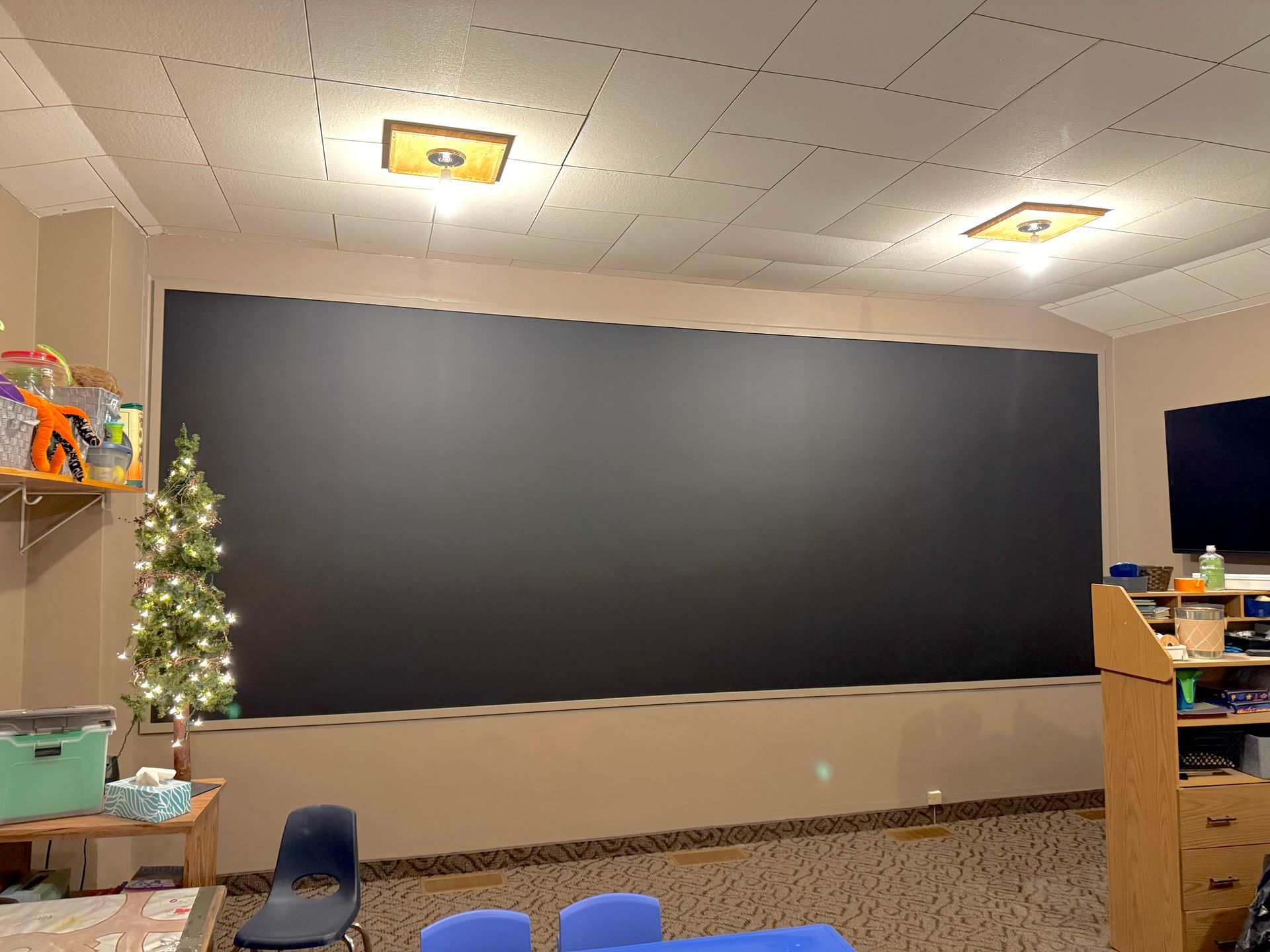 A classroom with a large blackboard and a christmas tree.