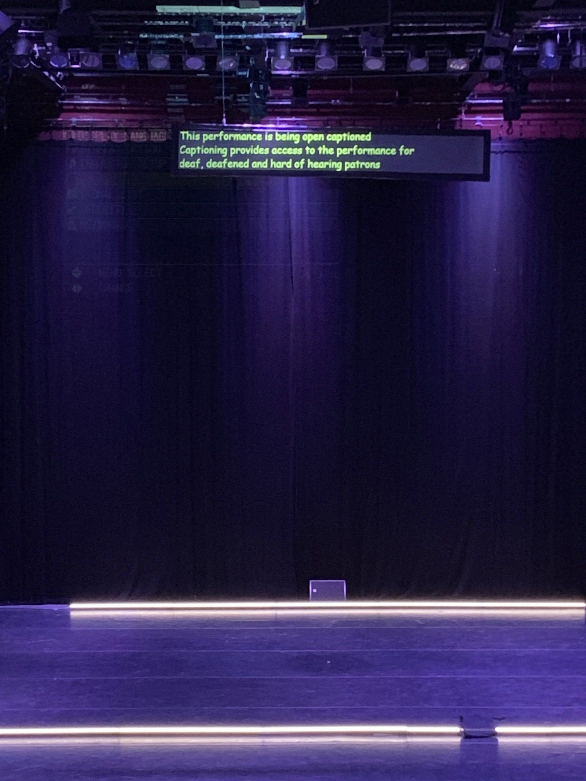 Hanging letterbox display of captions over empty stage.