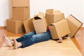 Man lying under piles of boxes.