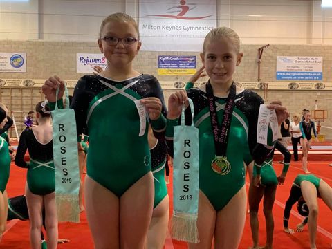Gymnasts with medals and ribbons smiling after their competition