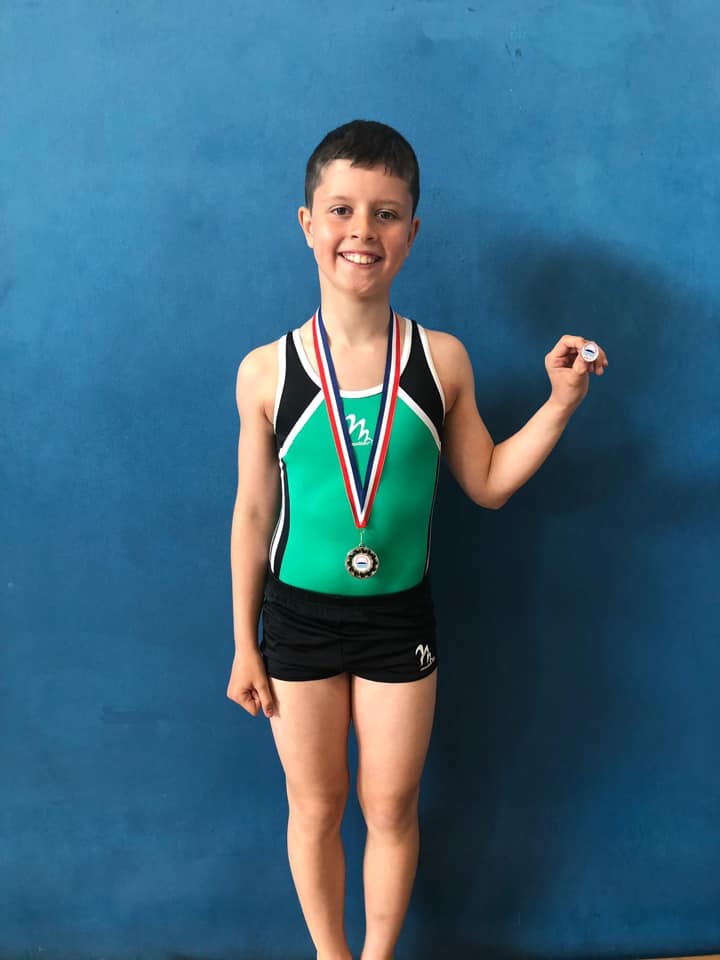 Gymnast wearing medals, smiling and celebrating after a competition