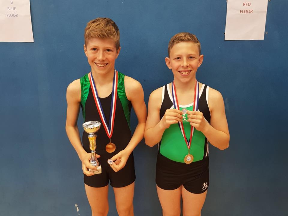 Male gymnasts with medals, achievement pins and a trophy
