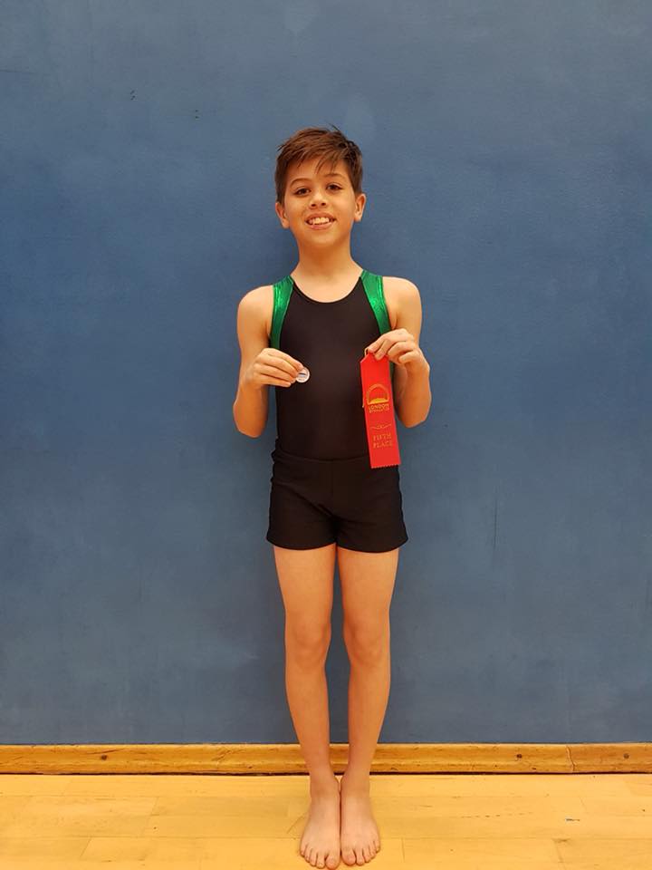 Male gymnast with a placing ribbon and an achievement pin