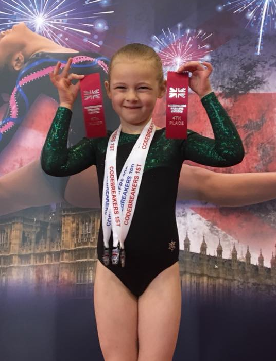 gymnast with medals and ribbons at the codebreakers competition