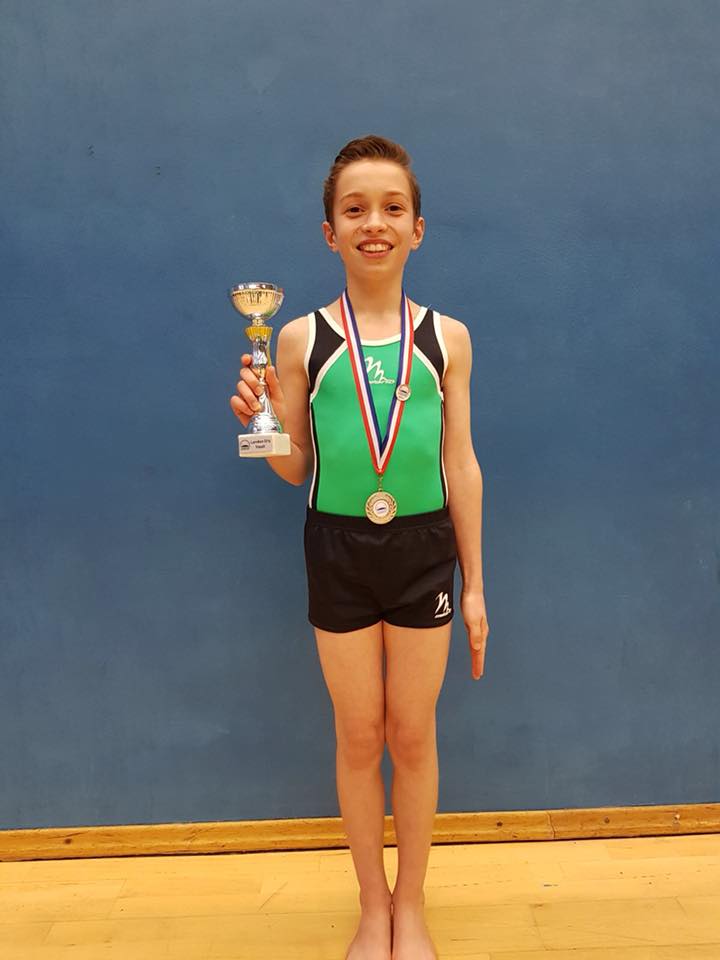 Male gymnast with trophy, medal and achievement pin