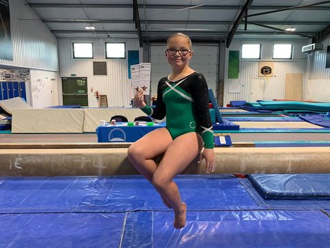 Gymnast sat on the beam smiling after their competition