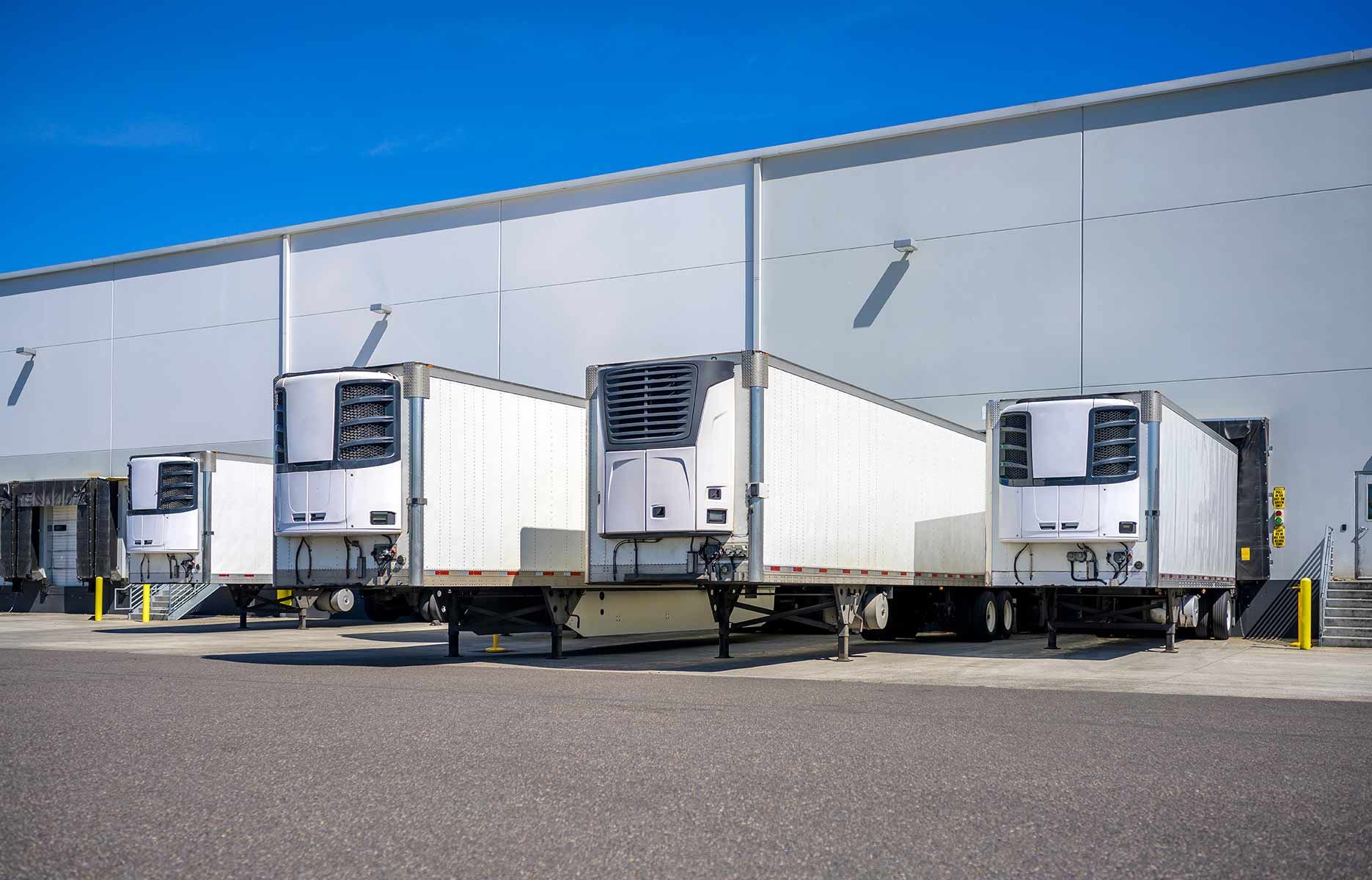 A Row Of White Semi Trucks Are Parked In Front Of A Warehouse — Auto Marvel In Mount Saint John, QLD