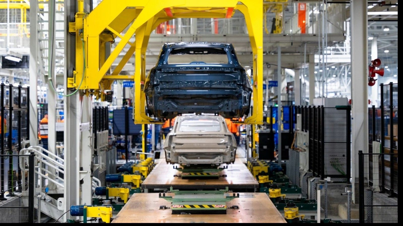 A car is being built in a factory on a conveyor belt.