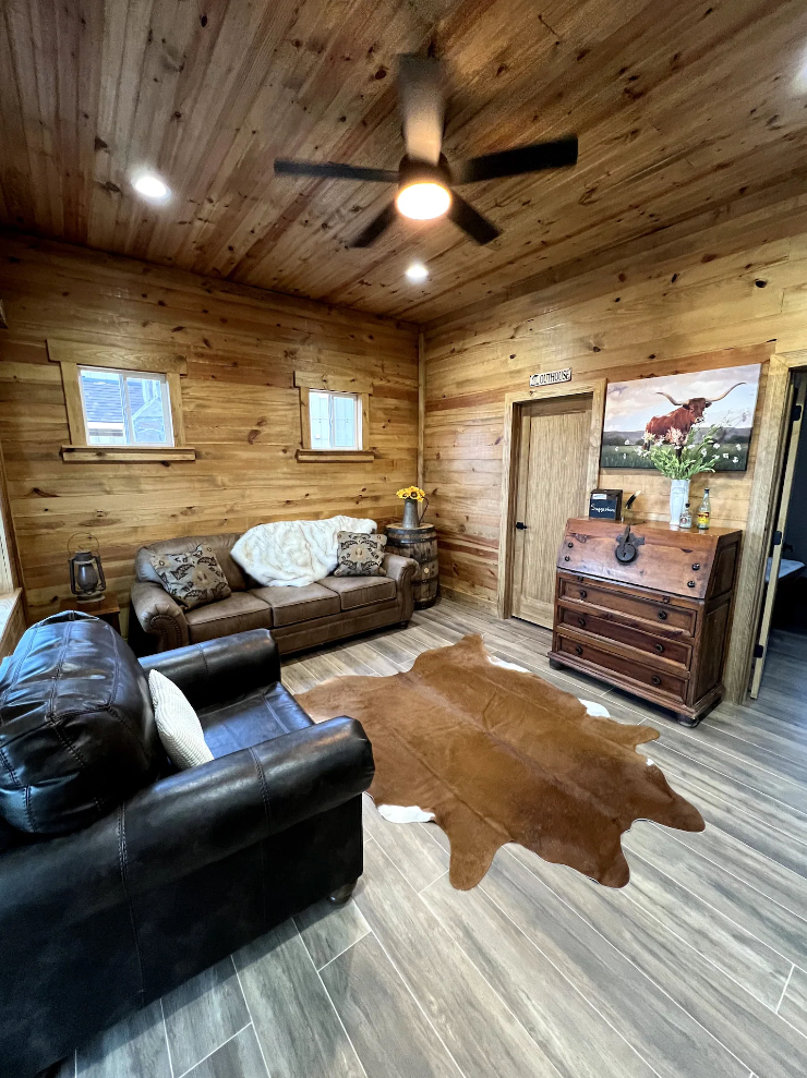 A living room with a couch , chair , rug and ceiling fan.