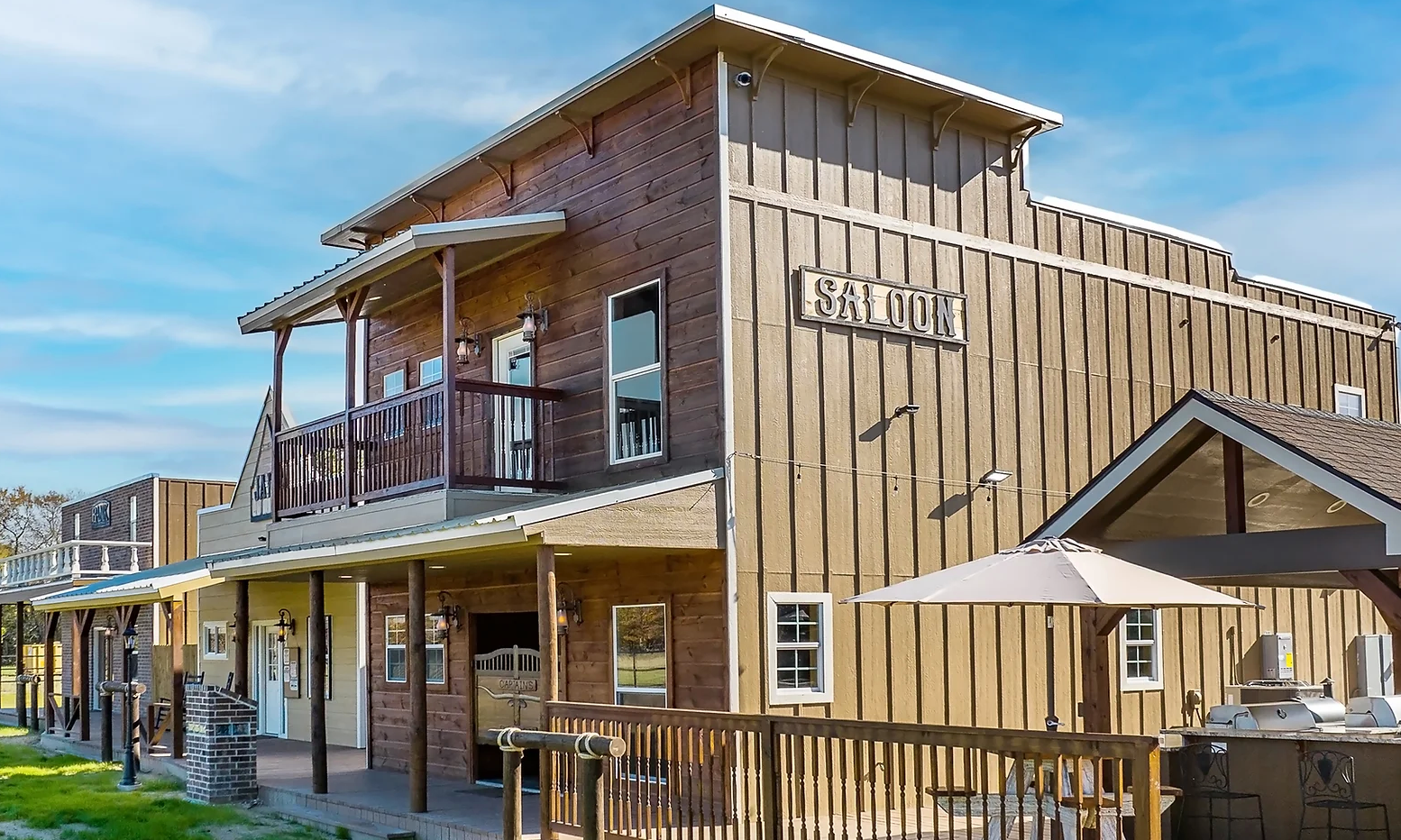A large wooden building with a balcony and umbrellas in front of it.