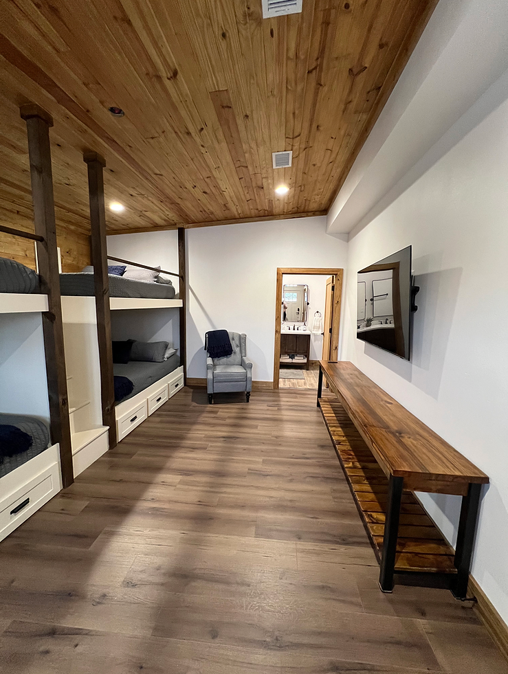 A large room with bunk beds , a chair , and a television.