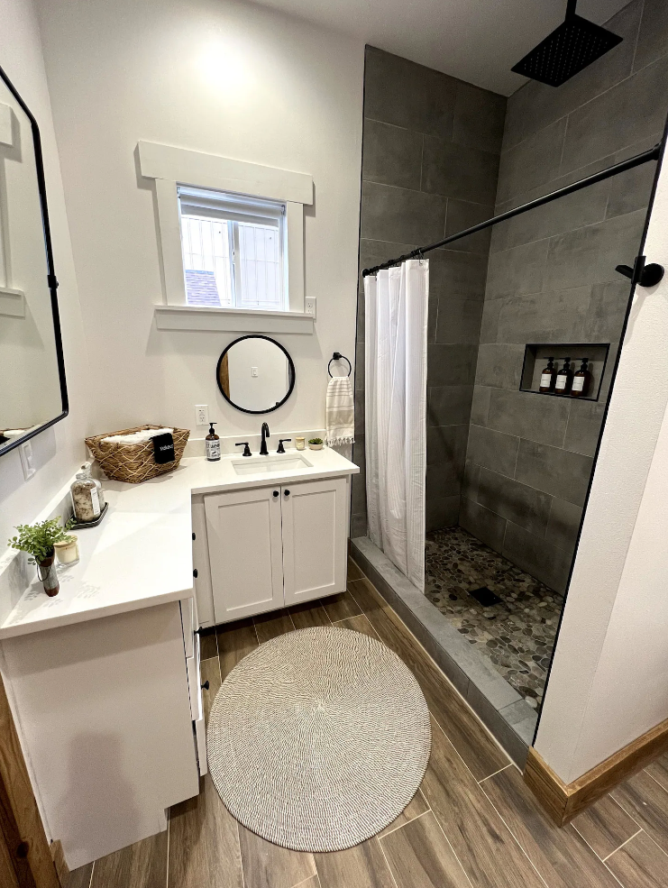 A bathroom with a sink , mirror , and walk in shower.