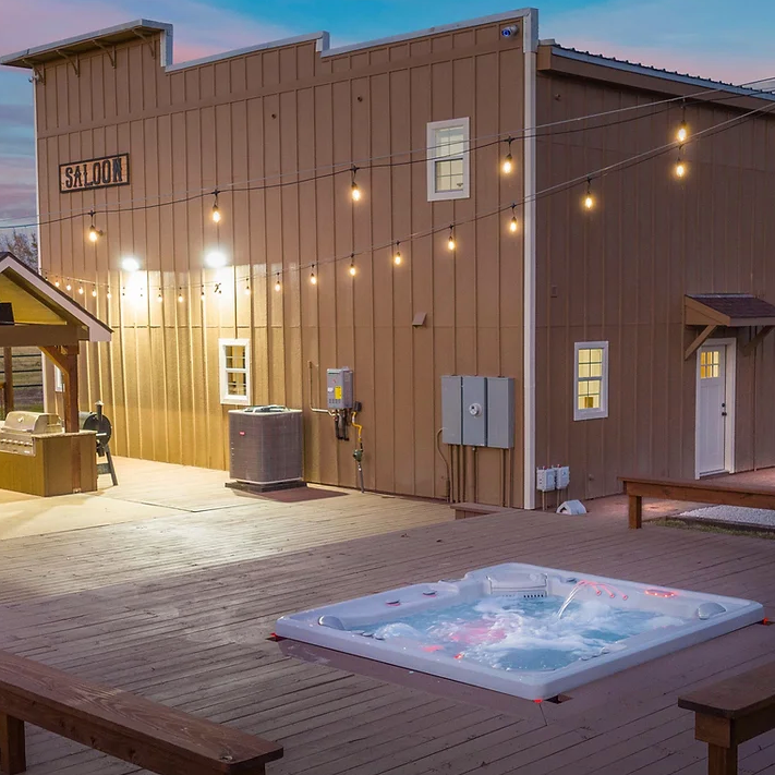 A hot tub is sitting on a wooden deck in front of a building.