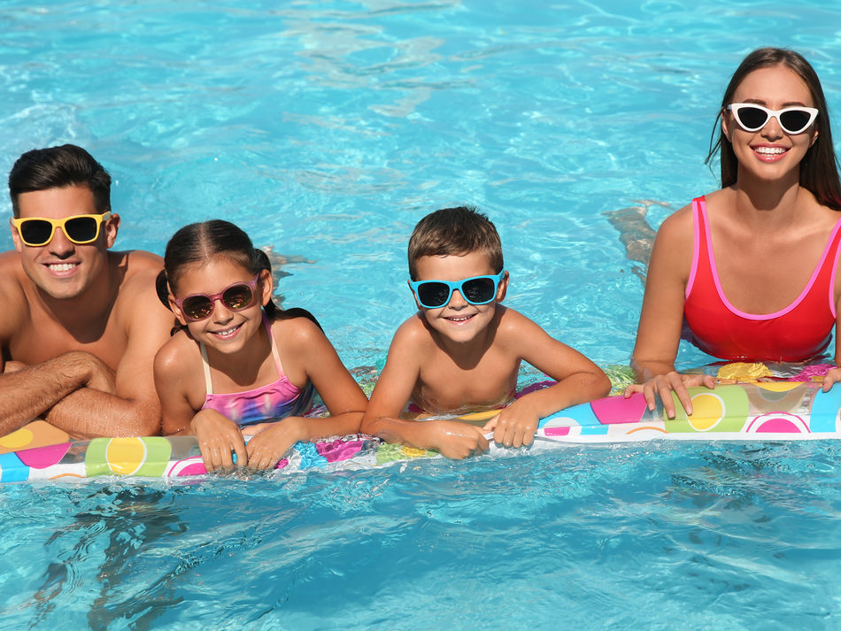 A family is laying on a raft in a swimming pool.