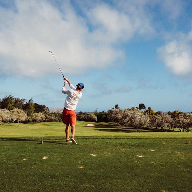 A man is swinging a golf club on a golf course