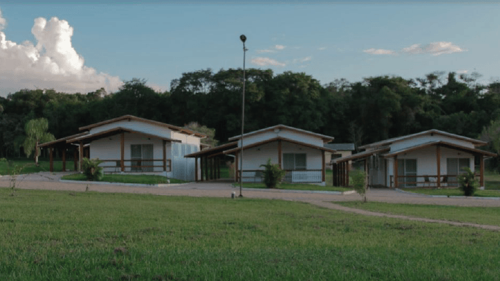 Uma fileira de pequenas casas estão localizadas no topo de um campo verdejante.