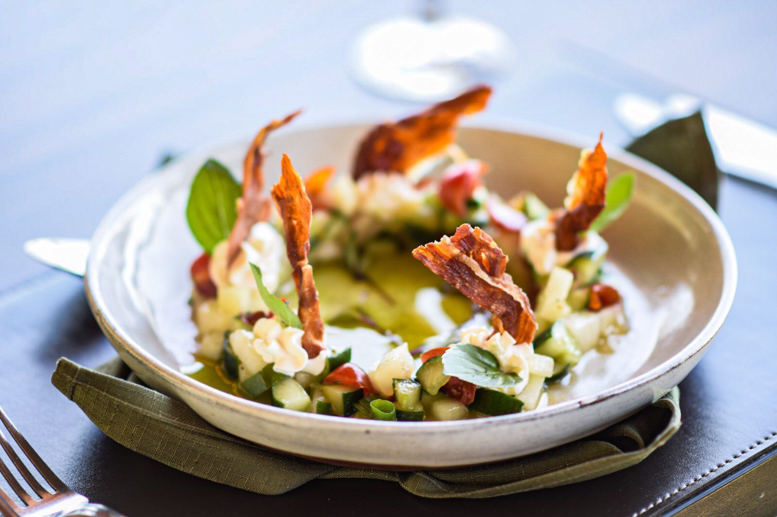Um prato de comida com vegetais e bacon sobre uma mesa.