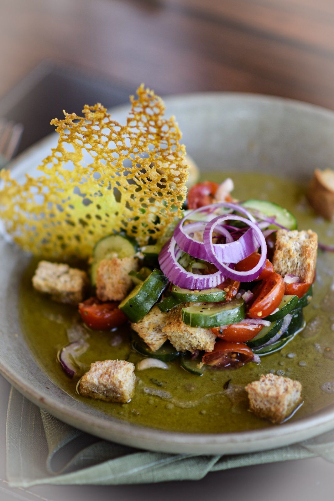 Um close de um prato de comida com croutons e vegetais em uma mesa.