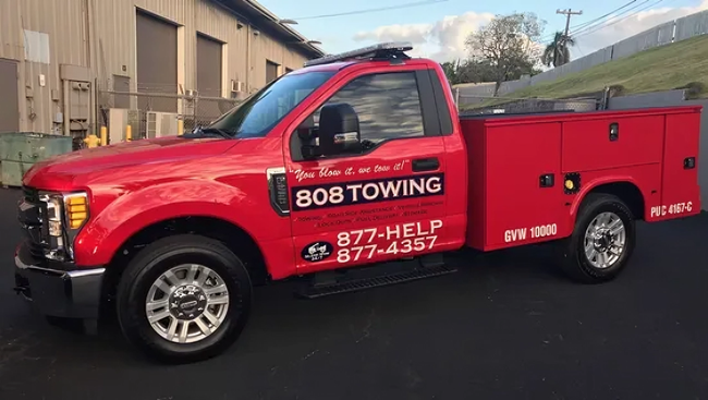 A red towing truck is parked in front of a building.