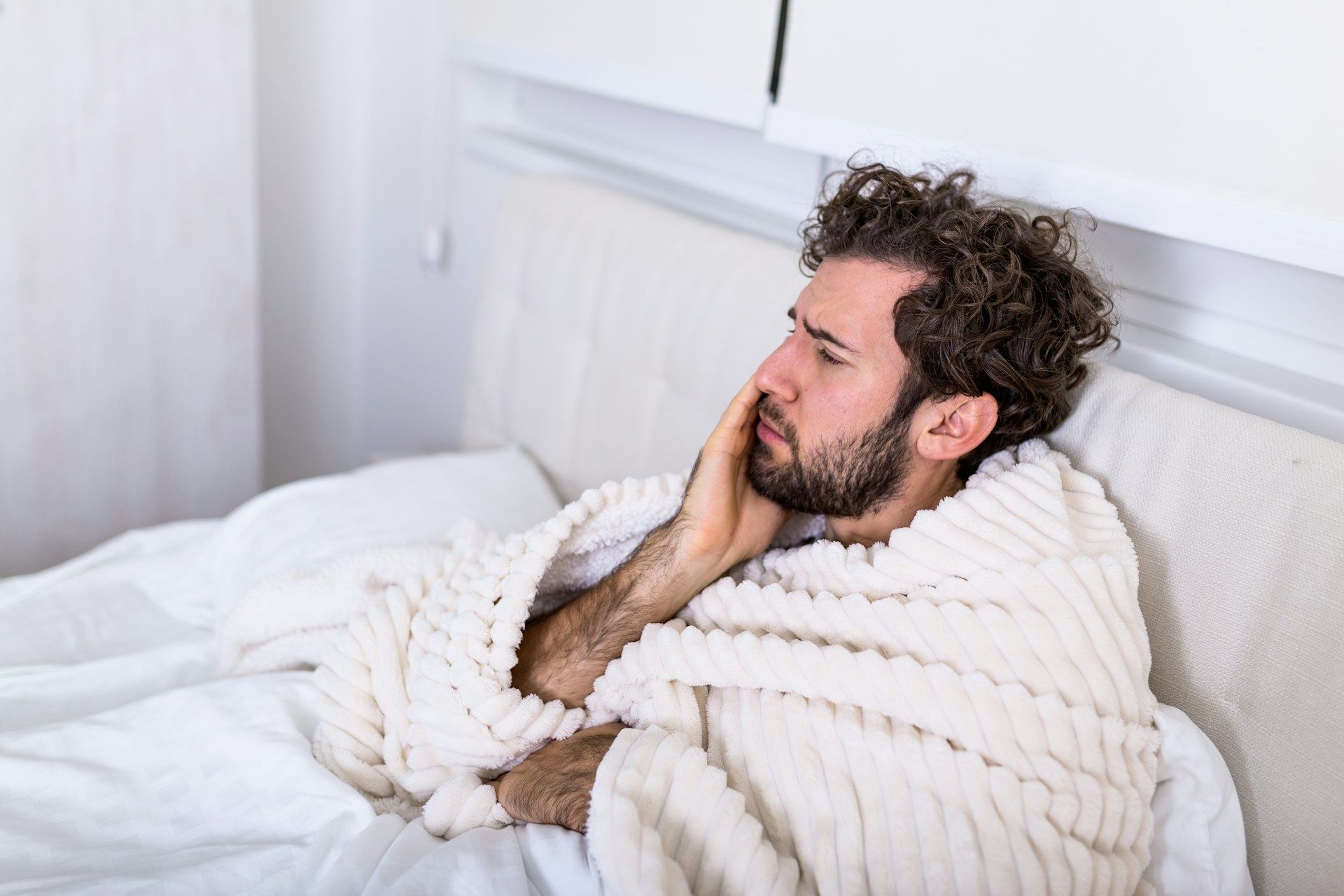 man in bed with oral pain