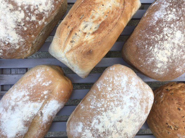A bunch of different types of bread are sitting on a rack.