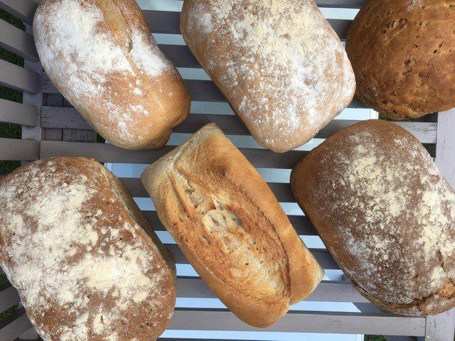Six loaves of bread are sitting on a wooden shelf