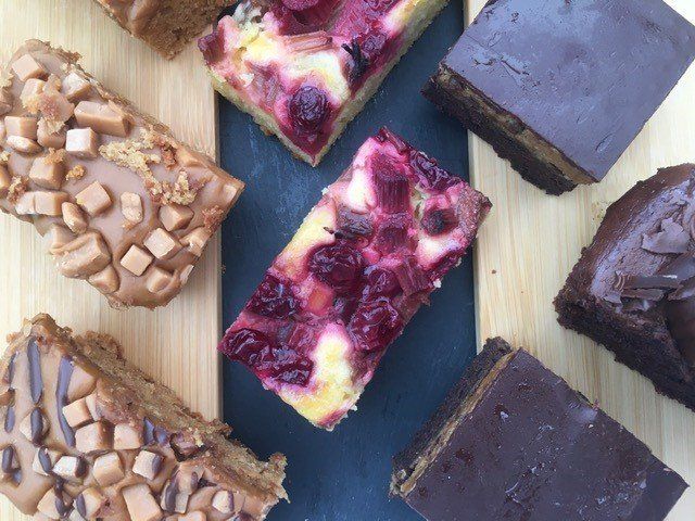 A variety of desserts are sitting on a wooden cutting board.