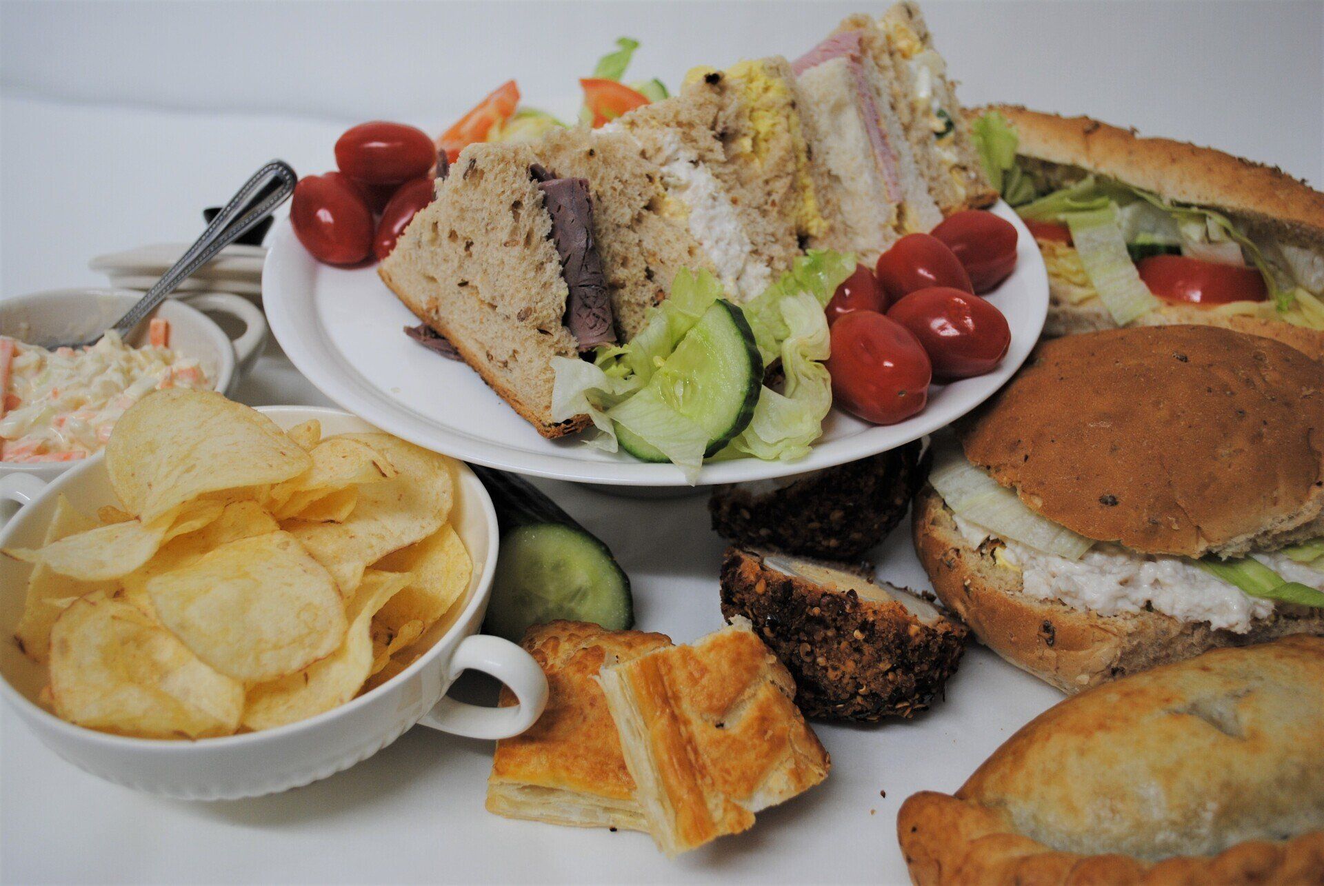 A table topped with plates of food including sandwiches and chips.