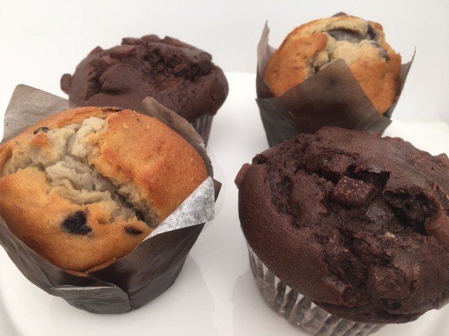 Four different types of muffins are on a white plate